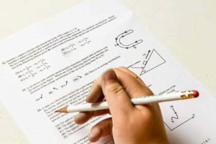 Candidato realizando um simulado de matemática financeira em um notebook com rascunhos e calculadora na mesa.